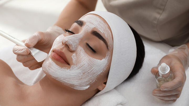 Woman lying in a cosmetic salon, chemical peel being applied to her face